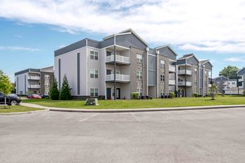 A large apartment complex with multiple buildings and a parking lot in front.